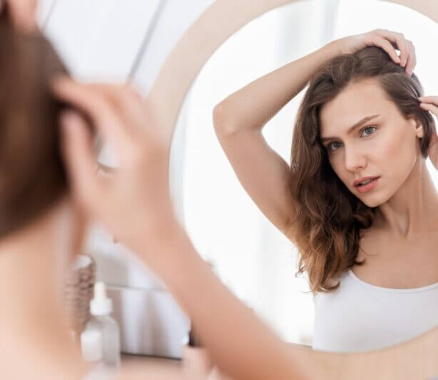 hair and skin health with tcm - woman looking at hair in a mirror